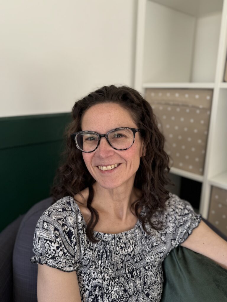 A trauma‑informed counsellor in a welcoming therapy room with green walls, natural light, and a comfortable seating area.